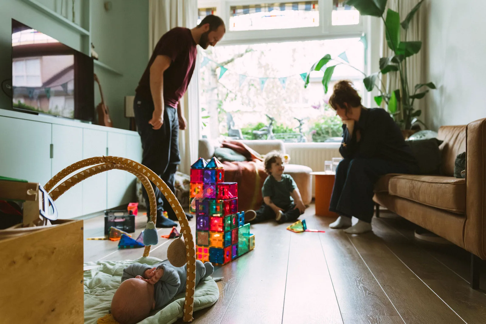 Een gezin speelt in de woonkamer tussen het speelgoed