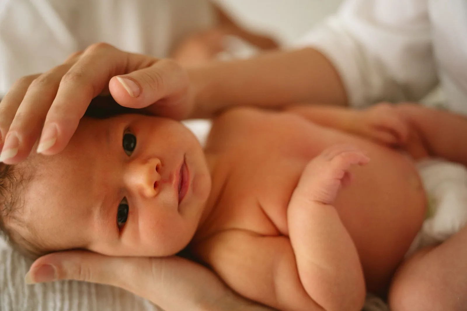 Een pasgeboren baby kijkt met open ogen omhoog
