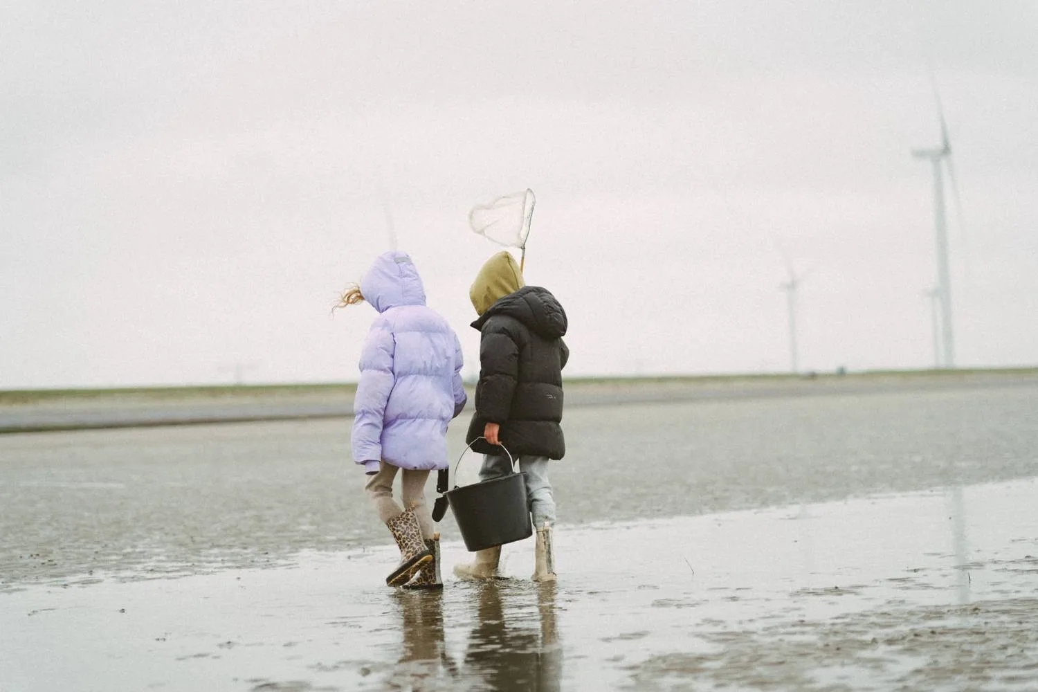 Twee kinderen lopen over het lege strand